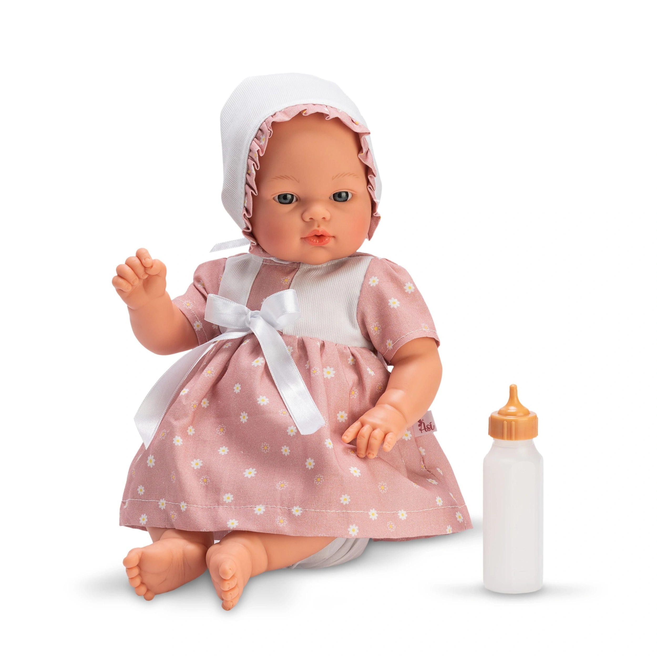 Koke doll in pink daisy dress with matching bonnet and white bow, sitting beside a baby bottle.