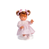 Guille doll with red hair pigtails, pink vichy dress, soft body, and expressive eyes, sitting on a white stand.