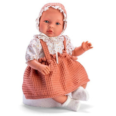 ASI Doll Leo, 46 cm, in floral shirt with cauldron strap skirt, wearing a bonnet, seated on a white surface.