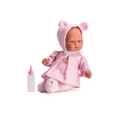 Oli Doll in pink outfit with heart-patterned hat and ears, sitting beside a pink baby bottle.