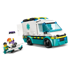 LEGO City Emergency Ambulance set featuring a white and teal ambulance with an open side door. A minifigure in green and black helps a skateboarder lying on a stretcher next to the ambulance, with medical accessories visible.