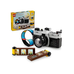 LEGO® Creator Retro Camera set featuring a retro-style camera in black and gray, with a moving lens and functional buttons. Includes a colorful brick-built film roll and a pack of stickers for customization, displayed next to its packaging.