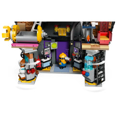 Minion standing in a colorful laboratory setting inside Gru's Family Mansion toy, featuring gadgets, screens, and playful decor.