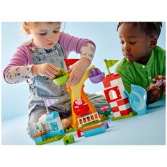 Two children play with the LEGO® DUPLO® Peppa Pig Funfair set, featuring colorful pieces like a Ferris wheel and a slide.