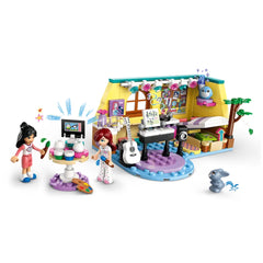Two LEGO Friends minidolls, one with long dark hair and one with red hair, explore Paisley's colorful room. A piano, a painting station with colorful pots, and a pet bunny enhance imaginative play. The room features vibrant decorations, a bed, and a window with a view.