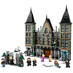 LEGO Harry Potter Malfoy Manor construction set featuring a detailed model of the mansion with pointed towers and iconic architectural elements. The scene includes six minifigures: Draco Malfoy, Harry Potter, Bellatrix Lestrange, Hermione Granger, and more, positioned around the set with a decorative gate and magical accessories.