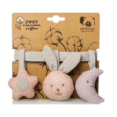 Pink stuffed star, bunny, and crescent moon on a grey ribbon, made from 100% cotton, against a brown Artesavi packaging.