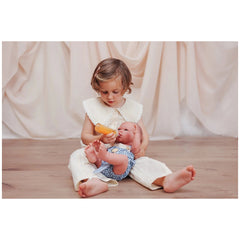 ASI Dolls - Pablo and Maria Vinyl Dolls showcased with a child in a white dress, engaged with a small toy on a wooden floor.