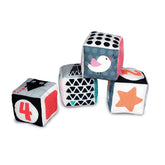 Black & white soft activity blocks for babies, featuring geometric patterns and vibrant colors, stacked against a white backg