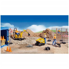 Construction play scene with toy figures, yellow digger, JCB truck, safety barriers, and tools on gravel under a blue sky.