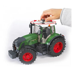 Hand rotating the steering wheel on a green Bruder Fendt 936 Vario toy tractor with red wheels.