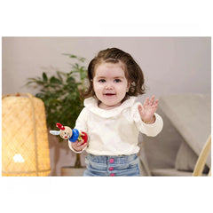 Baby wooden rattle rabbit in a child's hand, with a smiling child and indoor setting in the background.