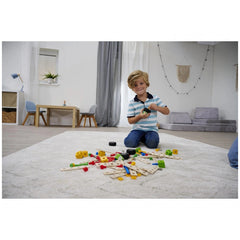 Eichhorn construction set toys are being enjoyed by a smiling boy sitting on a white carpet in a modern, well-lit room.