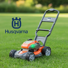Husqvarna toy lawn mower in orange and black placed on green grass, featuring the Husqvarna logo and AWD symbol.