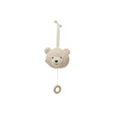 Light beige teddy bear stuffed animal hanging from a string attached to a dark brown circular object against a plain white ba
