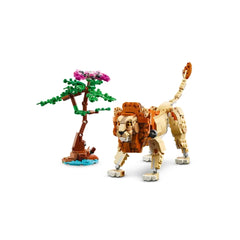 A detailed LEGO lion model with intricate fur patterns stands beside a small tree with pink flowers, set against a white background.