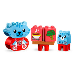Blue and red LEGO® DUPLO® animal figures include a happy kitten and a sad bear cub next to a table with food blocks, illustrating daily routines.