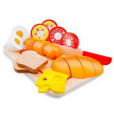 New Classic Toys cutting set featuring a wooden board, plastic eggs, bread, cheese, ham, and a red butter knife.