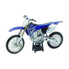 Blue die-cast motorcycle with white and silver accents, featuring a matte finish, chrome exhaust, and textured off-road tires