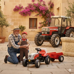 Rolly Toys Rollykid Steyr 6165 CVT tractor in red and black, with a man and child on a stone-tiled ground near a flowered bui
