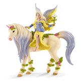 Schleich Bayala fairy figure in a yellow dress with pink flowers and a white unicorn with translucent glittery wings.