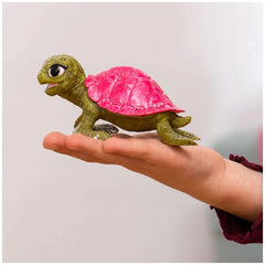 Pink sapphire turtle figurine with a green body, black eyes, and a pink shell, centered in a close-up view.