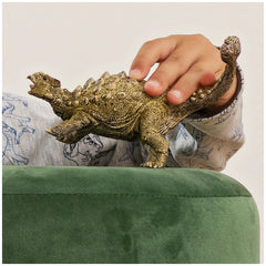 Ankylosaurus figurine held in a hand, resting on a smooth green surface, showcasing its textured, naturalistic colors.