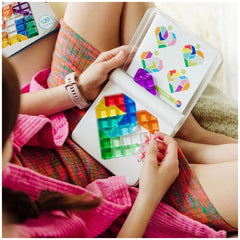 Smart Games - IQ Love logic puzzle displayed on a white laptop held by a person in a pink garment with crossed legs.