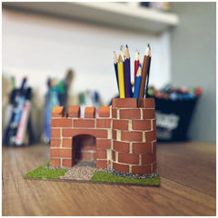 Teifoc castle model made of interlocking red bricks features a central archway, placed on a natural wooden surface.