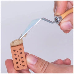 Teifoc trowel tool is shown alongside hands cutting textured fabric with metallic scissors featuring a wooden handle.