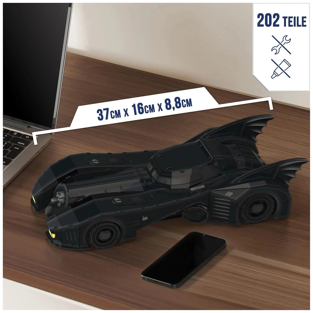 4D Build DC Batman Retro Batmobile 3D Puzzle Model Kit is a sleek black toy vehicle with bat-like wings on a wooden surface.