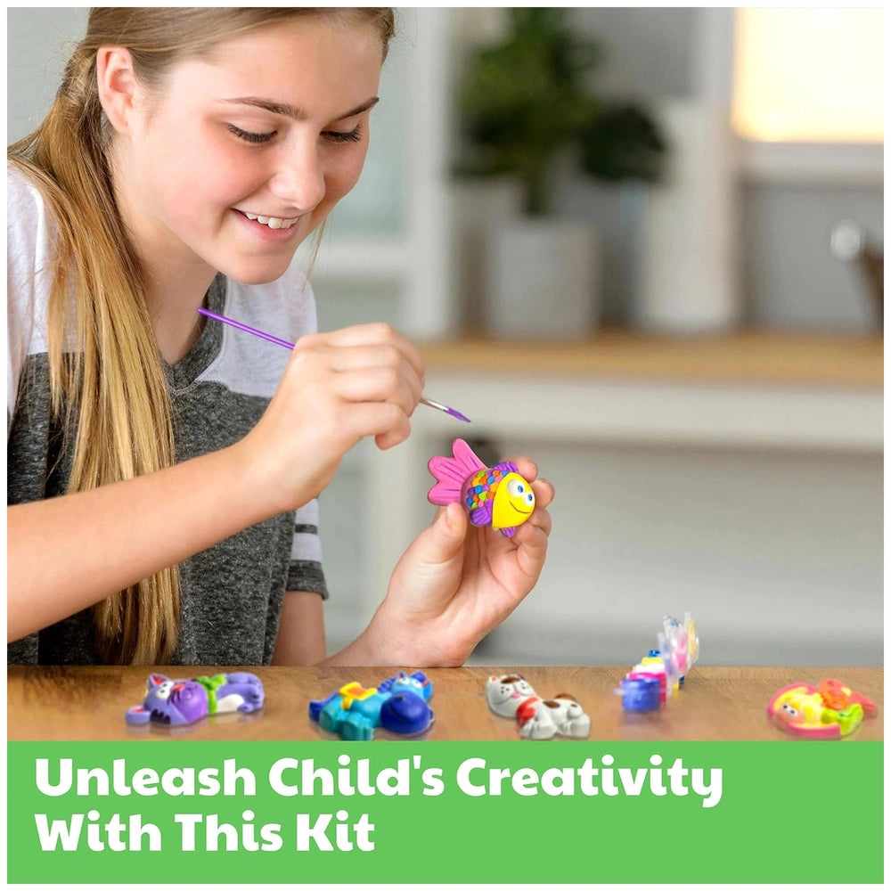 4M Mould & Paint Mermaid kit displayed as a young girl smiles while holding a purple object on a wooden table.