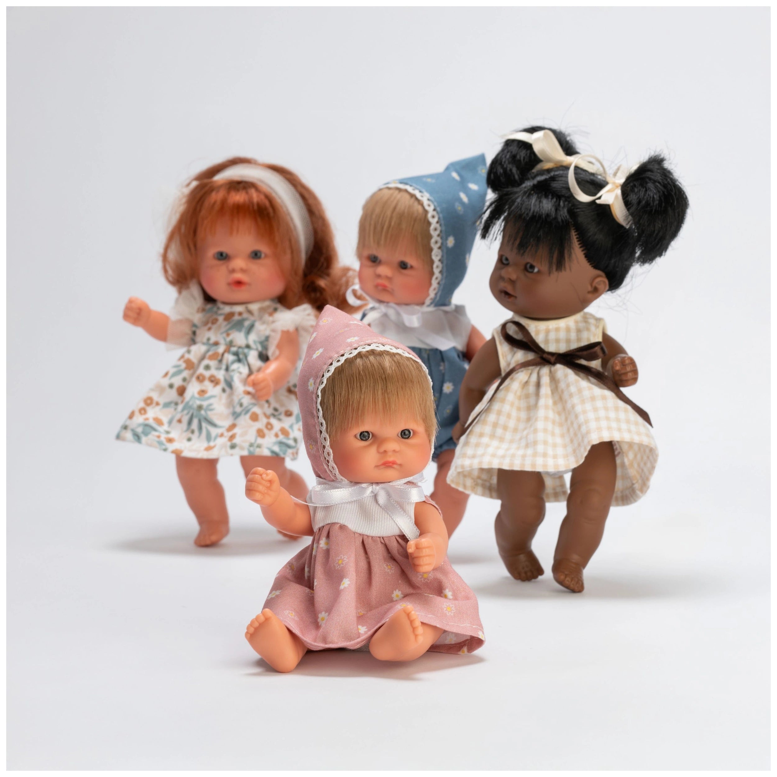 Four ASI Dolls from the Bonboncin Collection in colorful dresses, sitting and standing together.