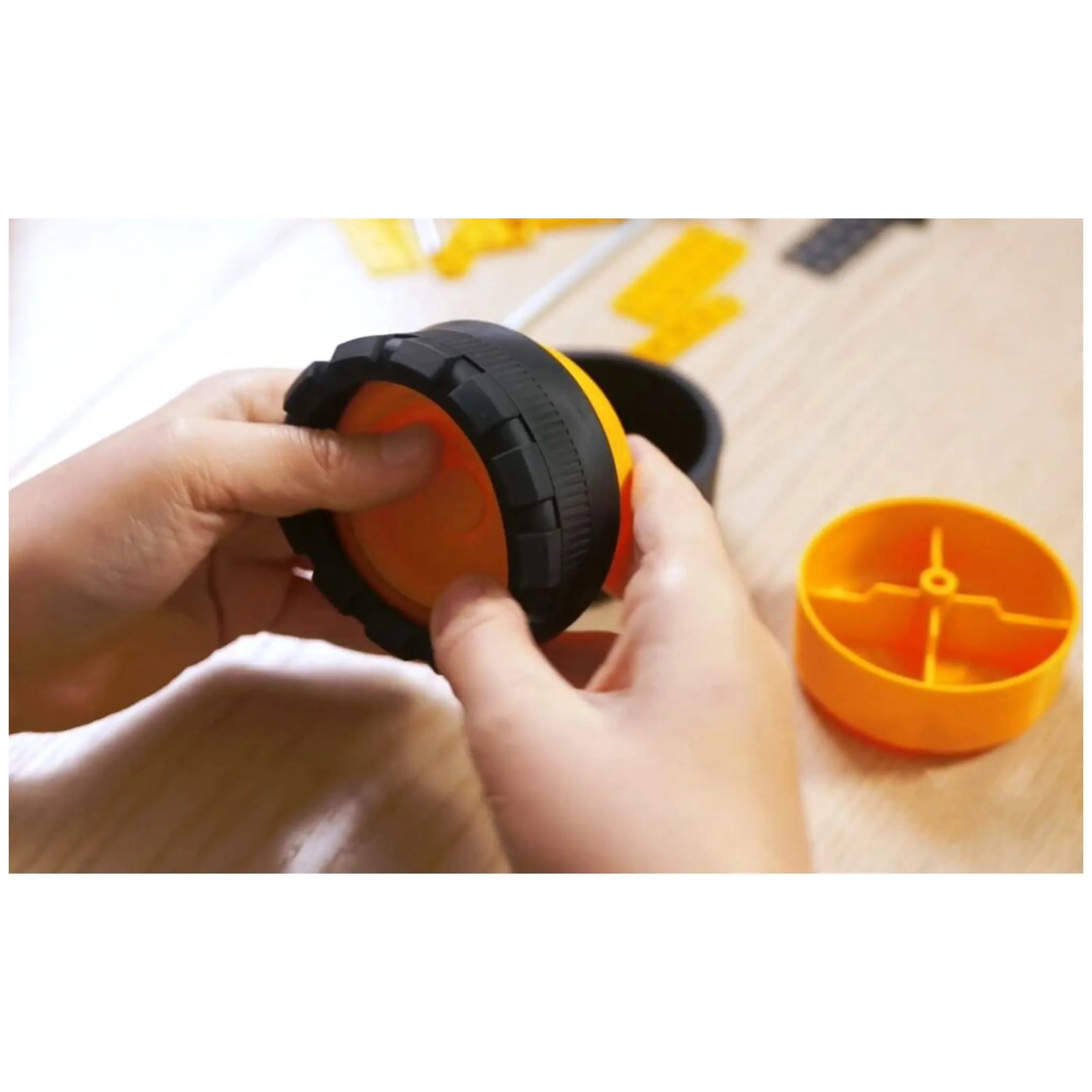 Child assembling an orange and black wheel from the Alexander Pro Muck Truck Constructor set.