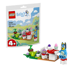 LEGO Bluey Tea Party set with Bluey figure and Babble-owl, featuring a colorful table, teapot, and vibrant cupcakes against a scenic background.