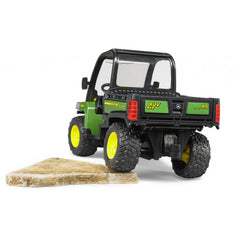 Green Bruder John Deere Gator XUV 855D toy on a rock, showing rear details and rugged tires.