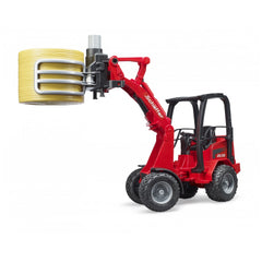Red Bruder Schäffer Compact Loader 2630 with bale gripper holding a yellow bale, showcasing detailed farm vehicle features.