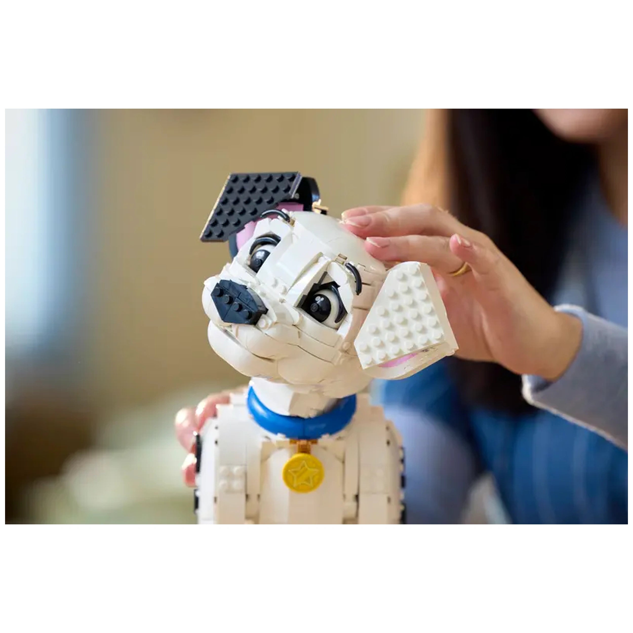 Dalmatian puppy LEGO model with detailed expressions, being gently touched by a hand, against a soft blurred background.