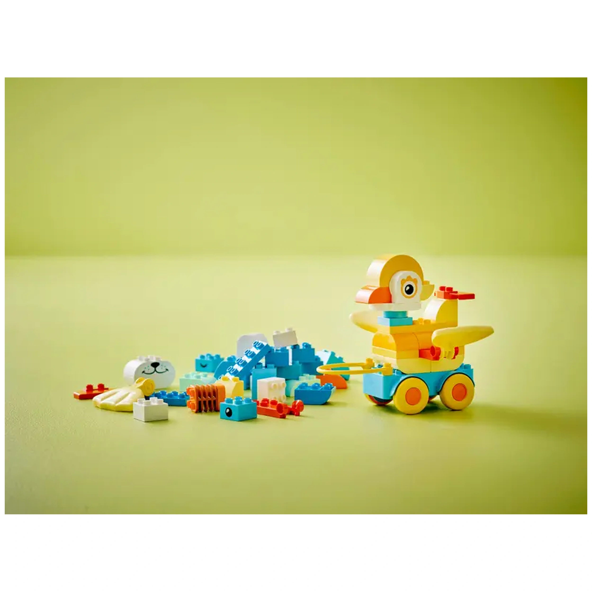 Colorful LEGO DUPLO construction set featuring a vibrant yellow duck on wheels, surrounded by various animal-themed building blocks and pieces.