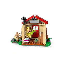 LEGO Animal Crossing set featuring Goldie the dog character sitting in a cozy red-roofed house with a picnic table outside.