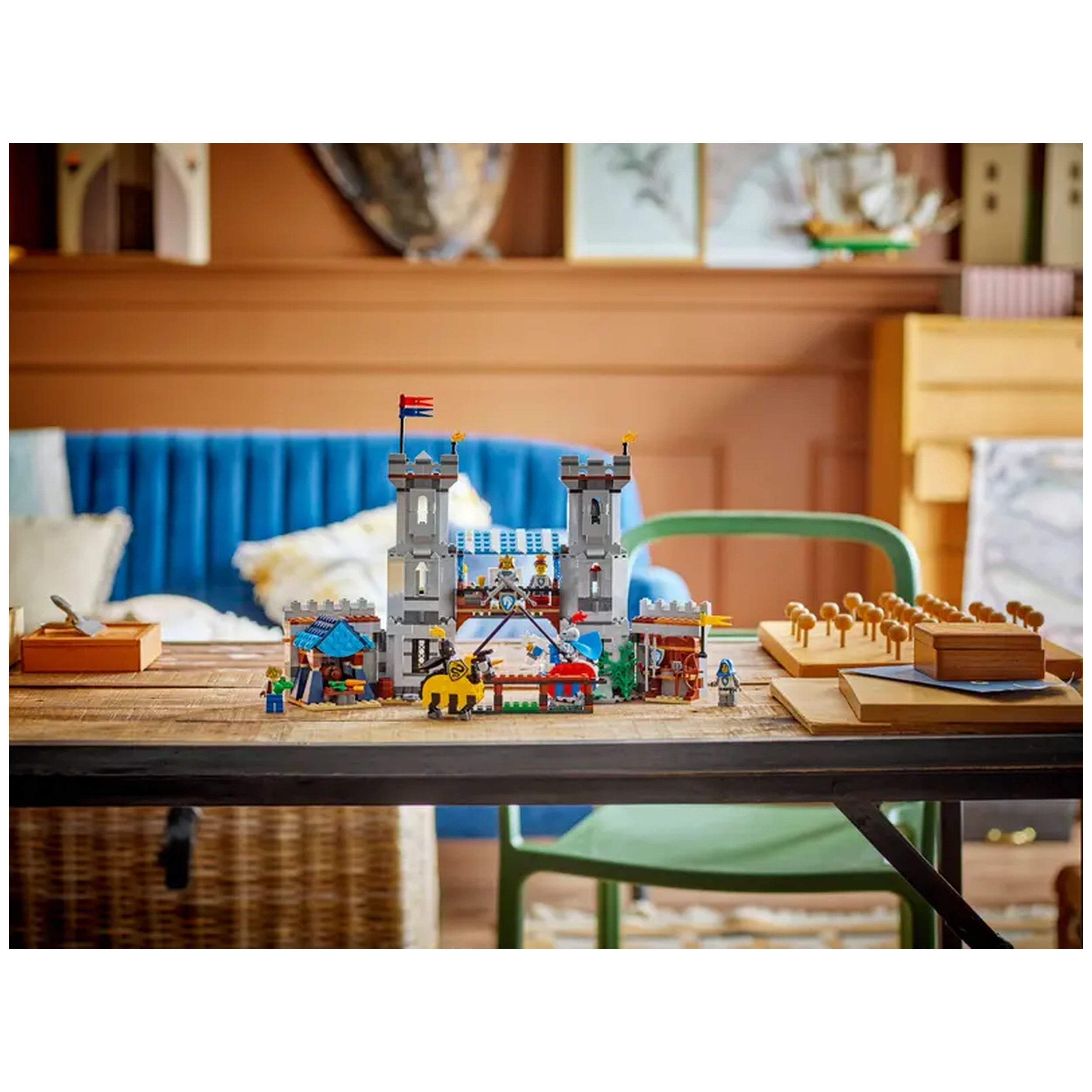 Colorful LEGO Creator 3in1 Medieval Horse Knight Castle set displayed on a wooden table, featuring towers, a drawbridge, and minifigures amidst a cozy room.