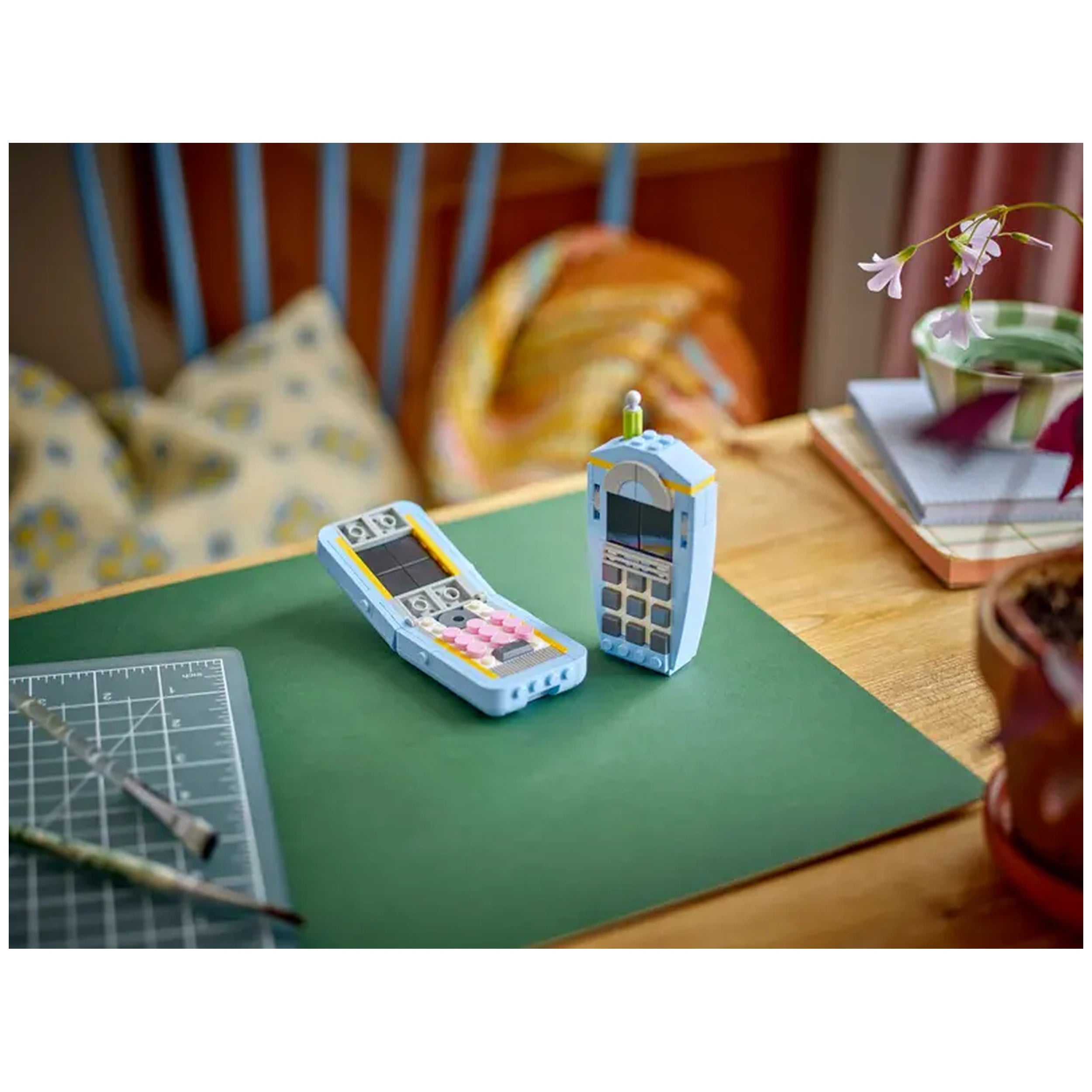 LEGO Creator 3in1 Retro Telephone set featuring a 1960s rotary phone and a 1980s phone, displayed on a green surface with craft tools nearby.