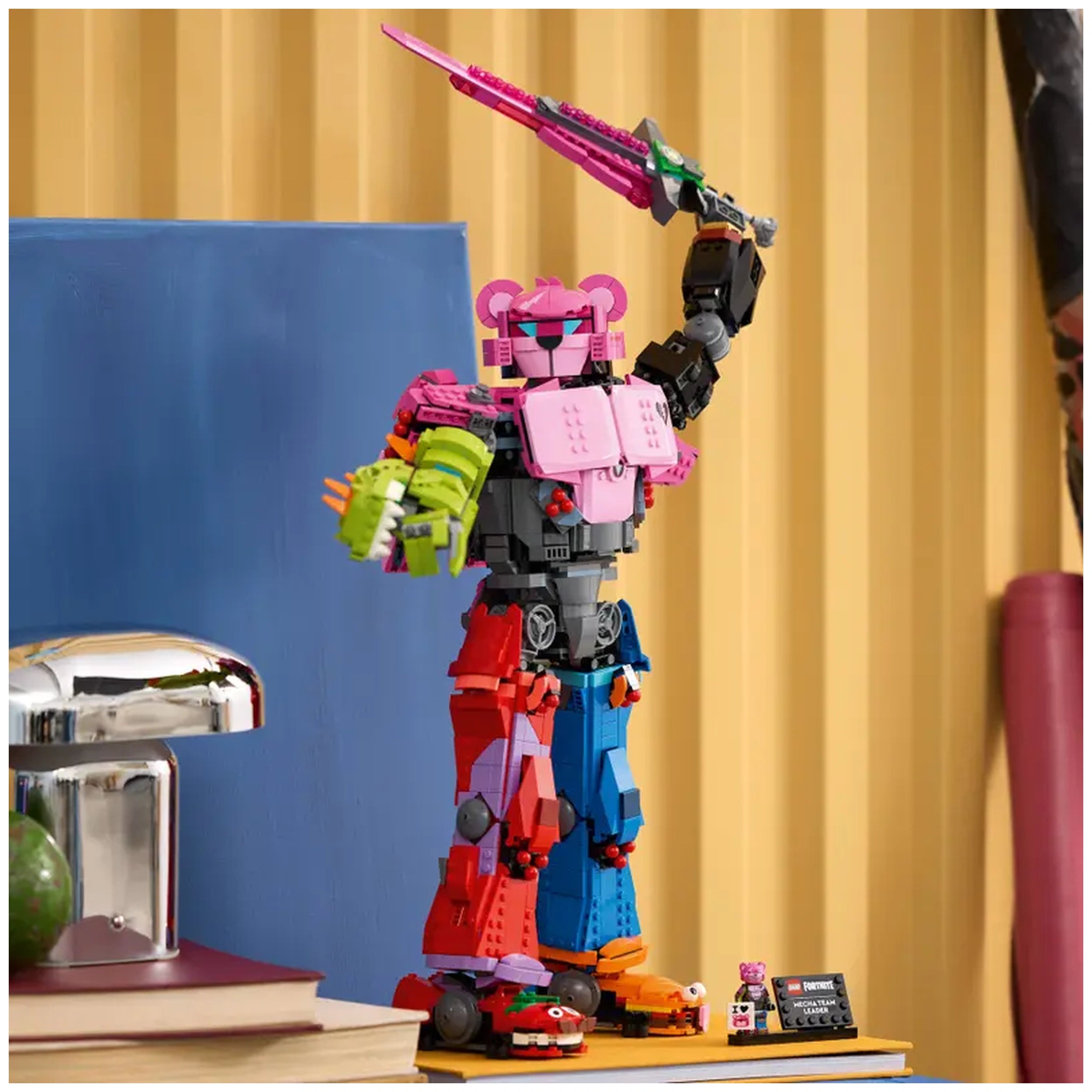 LEGO Fortnite Mecha Team Leader set displayed on a shelf, featuring vibrant colors, a pink figure holding a sword, with books and a shiny object nearby.