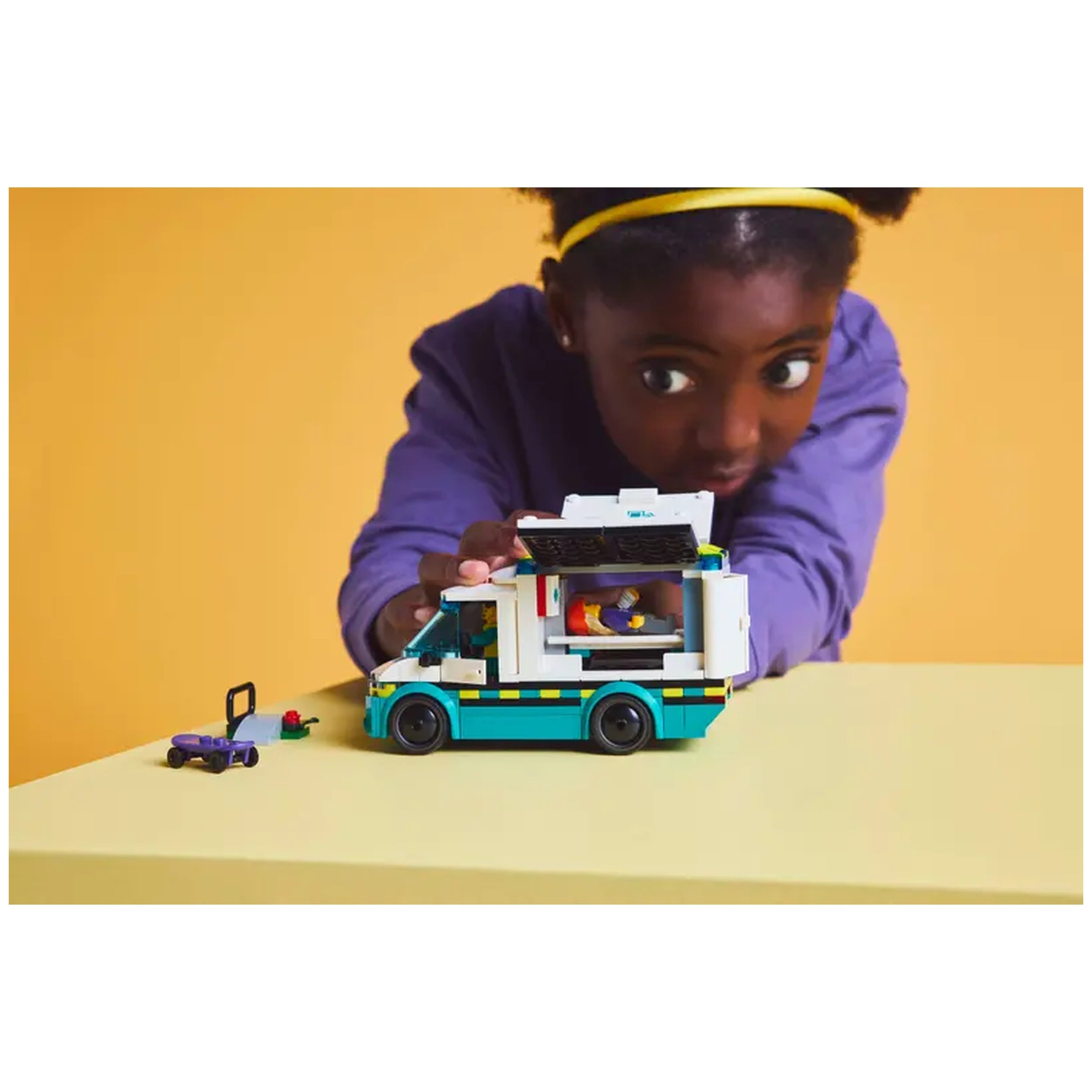 Child enthusiastically plays with the LEGO® City Emergency Ambulance set, featuring various medical accessories and a skateboard.