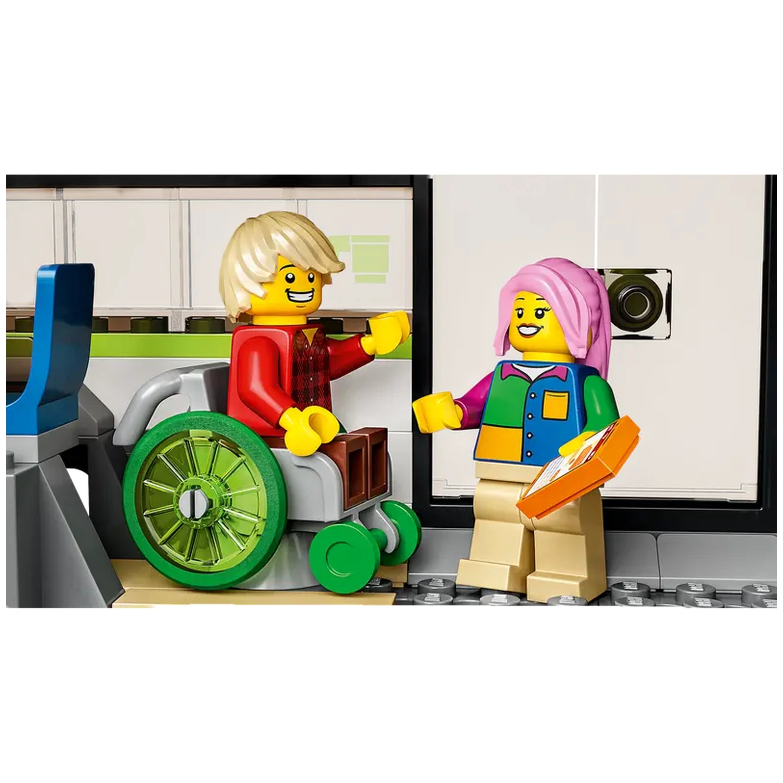Two LEGO minifigures interact inside a train car, one in a green wheelchair and the other holding an orange box. The setting features a modern, light-colored interior with seating and a food prep area.