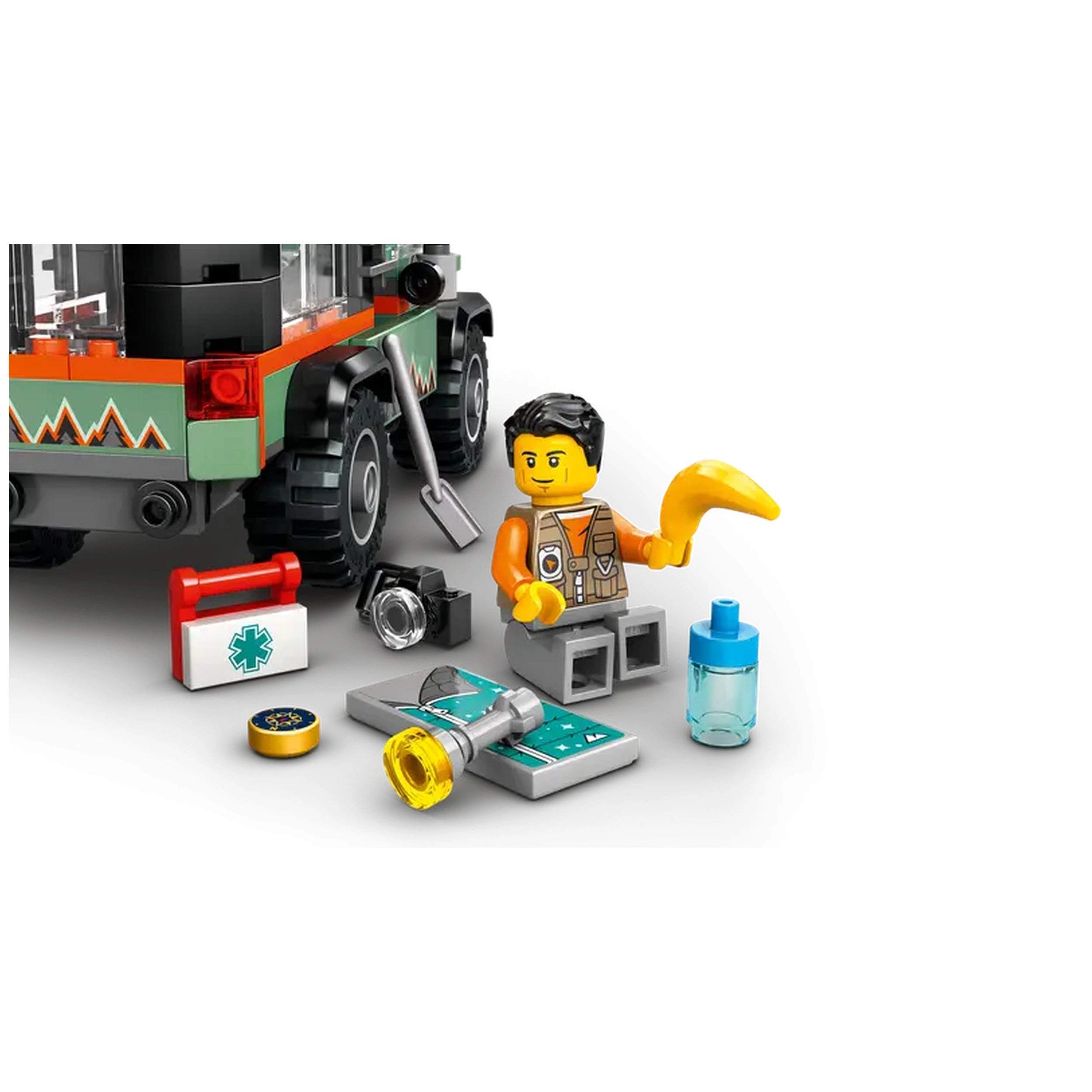LEGO® City Off-Road Mountain Truck set with a mini-figure wearing an orange vest, surrounded by a map, tools, a camera, and a water bottle, parked on rugged terrain.