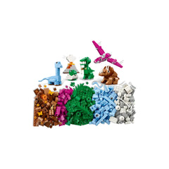 Colorful LEGO bricks arranged in groups, featuring dinosaur models like a blue brontosaurus, green T. rex, pink pterosaur, and brown triceratops. Various shades of green and brown bricks are included for building environments, along with palm leaves and accessories for imaginative play.