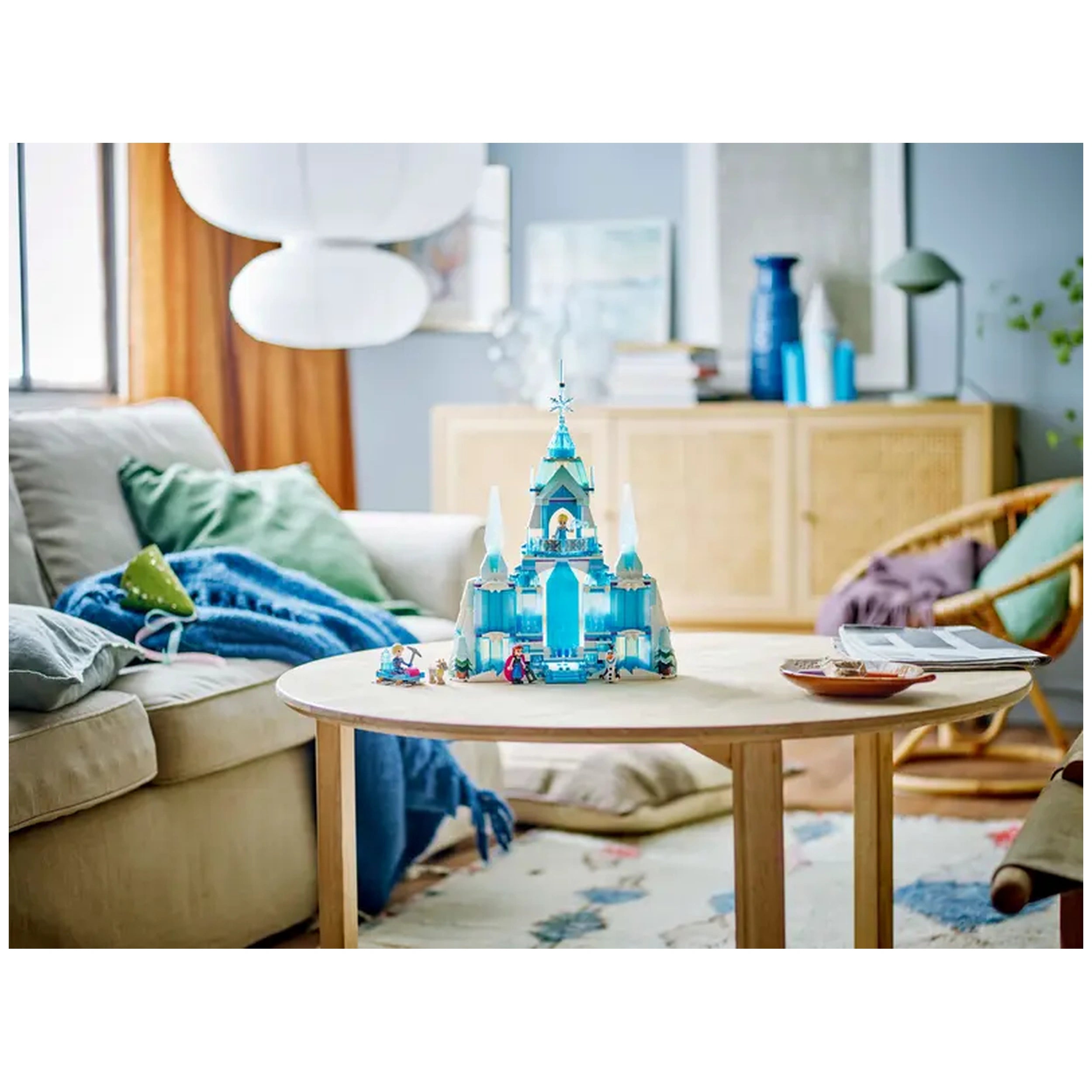 Colorful LEGO® Disney Frozen Elsa's Ice Palace set displayed on a round wooden table, surrounded by cozy furniture and decor elements.