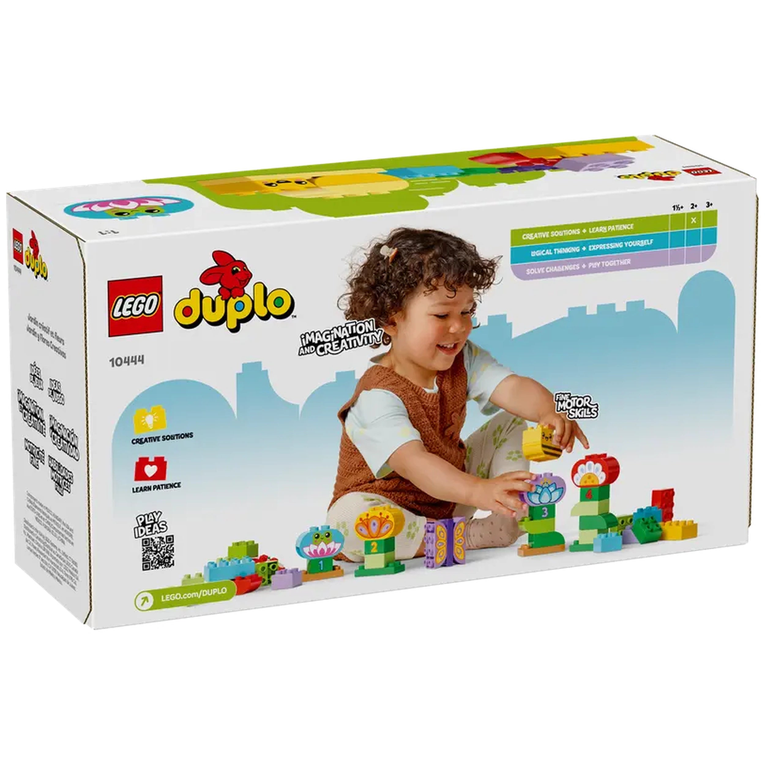 A joyful child with curly hair constructs a colorful garden scene using LEGO® DUPLO® bricks, featuring flowers and playful animal figures.