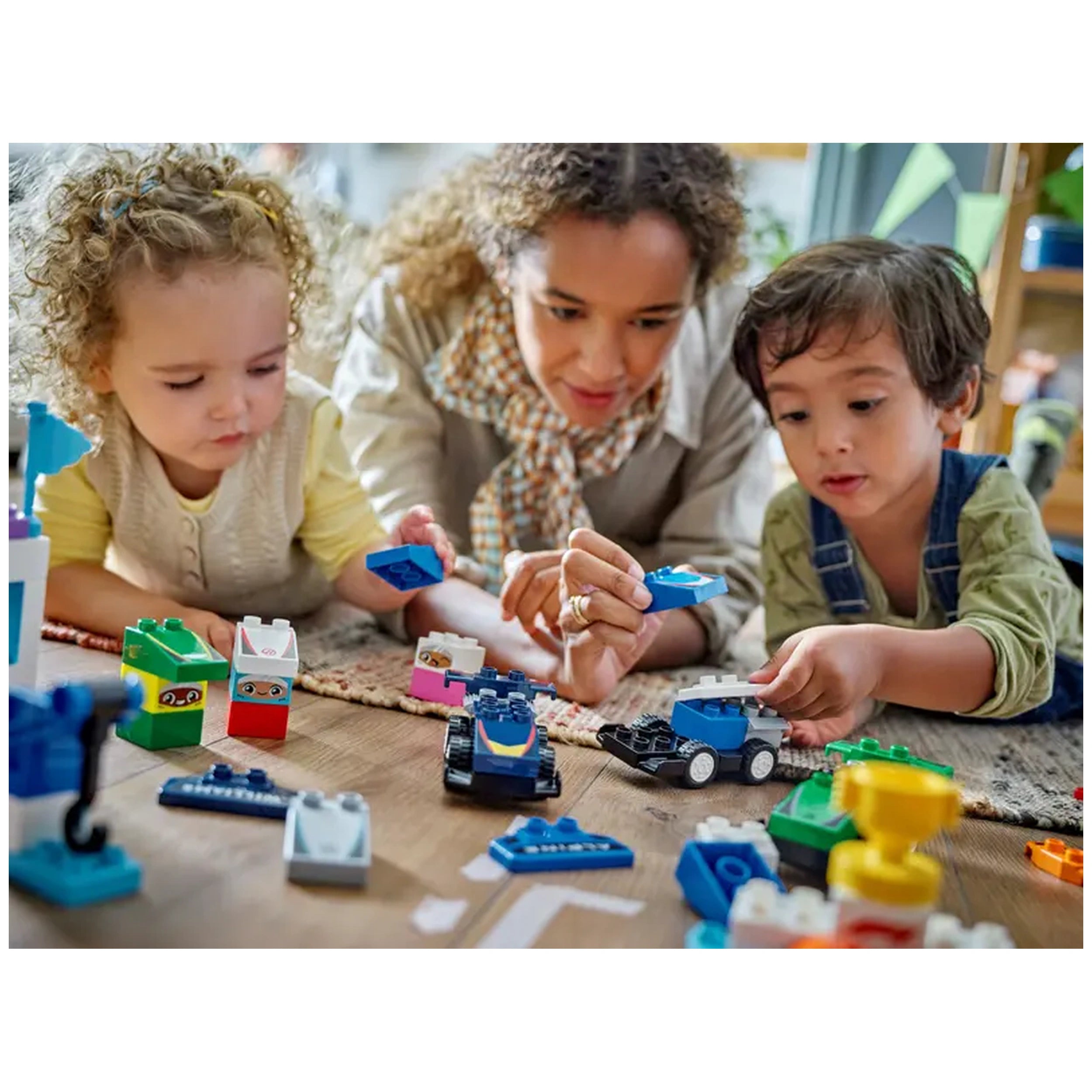 A woman and two children play on the floor, immersed in building with colorful Lego pieces, including race cars and accessories.